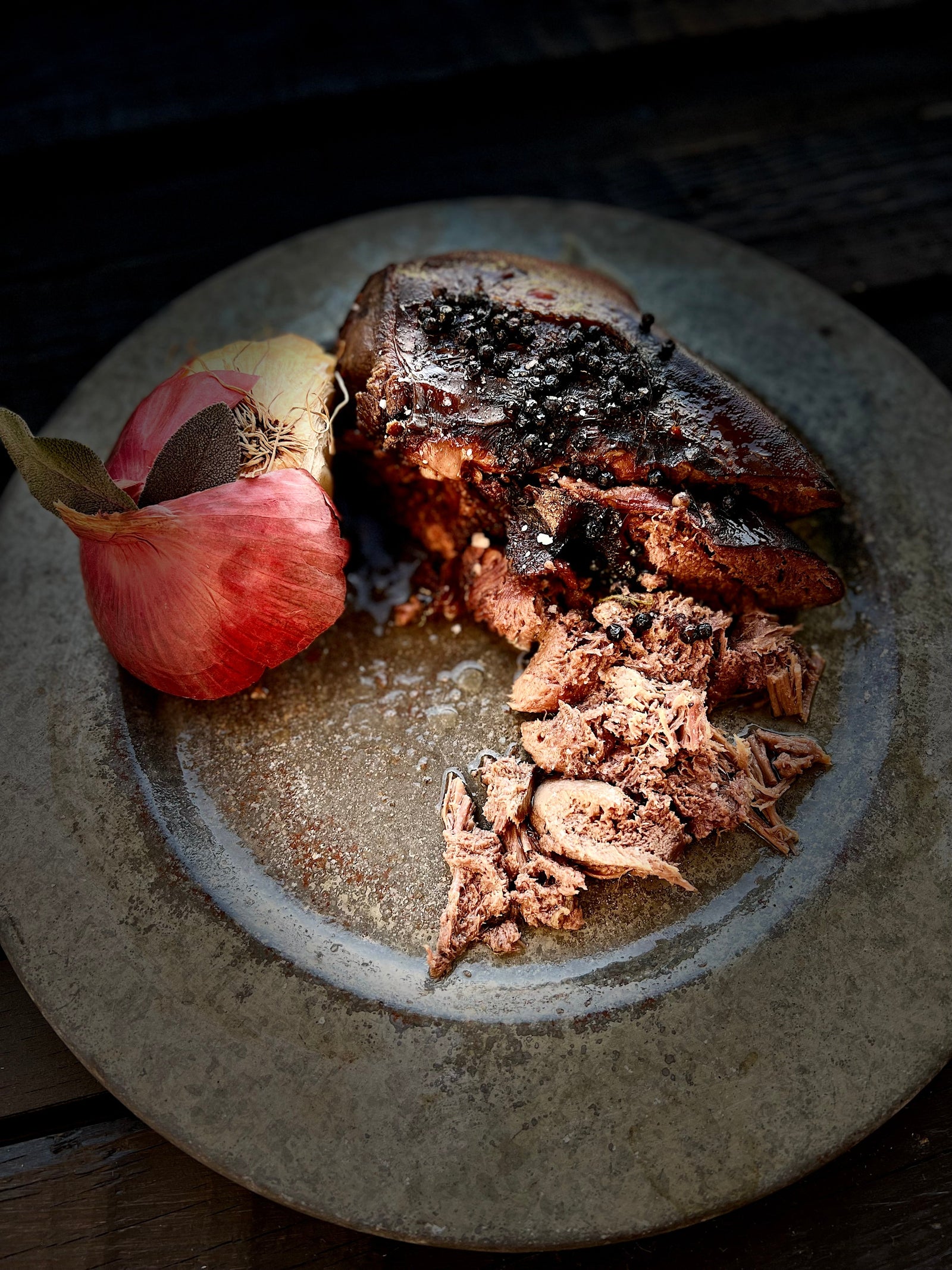 Raw beef tongue and herbs on a round cutting board